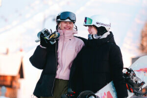 Laskettelija ja lumilautailija keväisen aurinkoisen rinteiden edessä Himoksella.