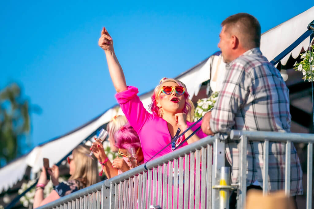 Pinkkiin vaatteeseen pukeutunut henkilö juhlii terassilla Himoksen Iskelmä Festivaalilla.