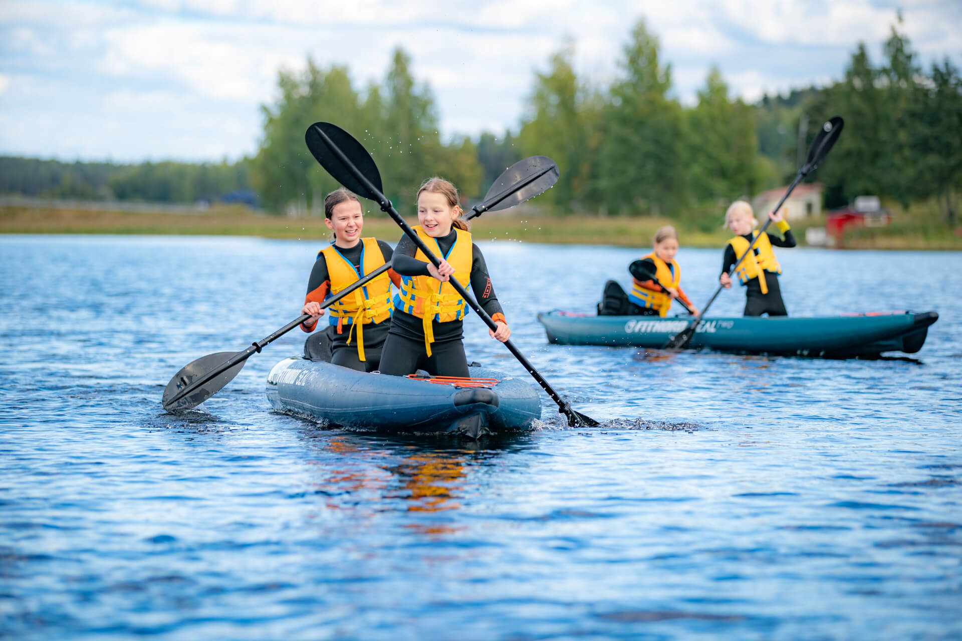 Neljä henkilöä melovat kahdella sup-laudalla keltaiset pelastusliivit yllään.
