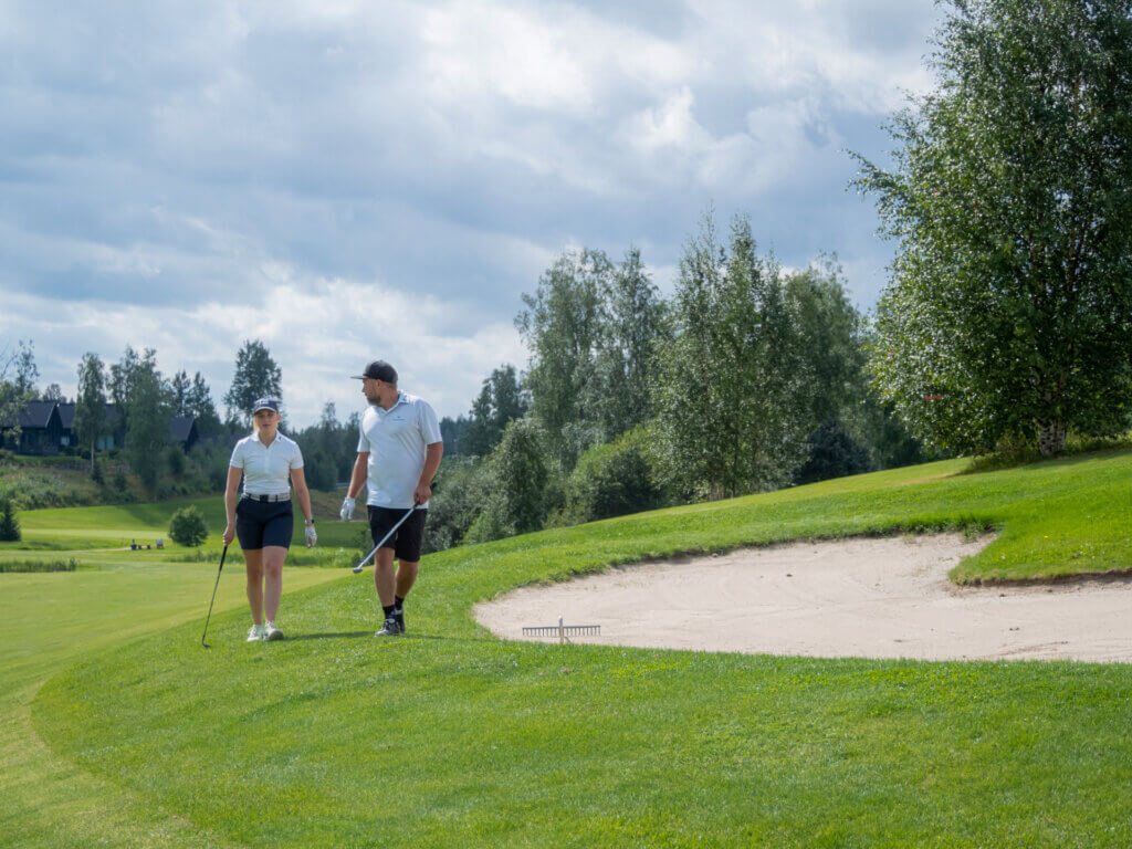 Pelaajat kävelevät Himoksen golfkentällä puolipilvisellä kelillä kesällä.