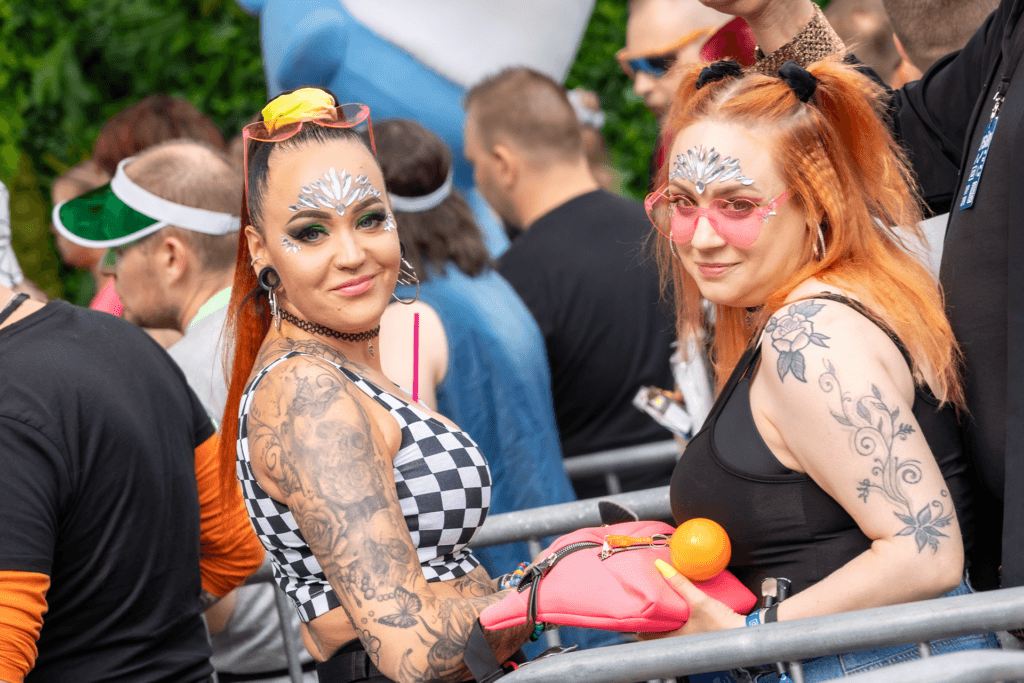 Kaksi henkilöä katsovat kameraan Jysäri-festivaaleilla. Molemmilla on paljon glitteriä kasvoissaan ja tatuointeja paljaissa käsivarsissaan. Hiukset ovat ylhäällä kiinni molemmilla.