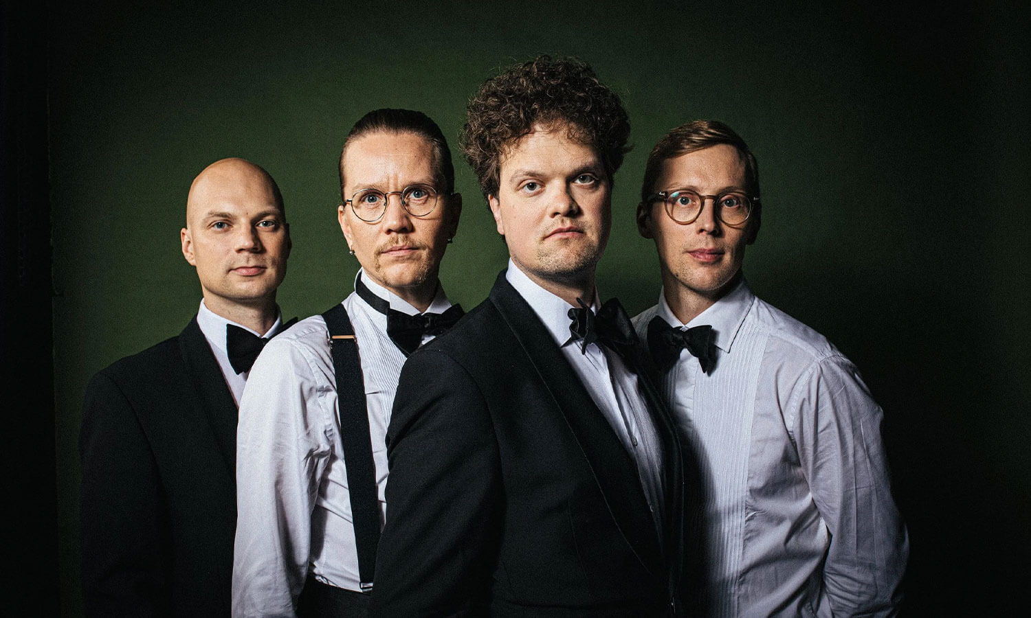 Slipovers-yhtyeen neljä jäsentä. Kahdella on tummat takit päällä, kahdella vaaleat paidat. Kaikki pukeutuneet pukuun ja rusetit kaulassa.