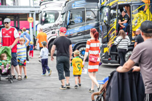 Ihmisiä kävelee Himos Truck Show´n tapahtuma-alueellav isojen ajoneuvojen välissä.