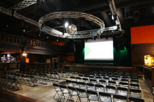 Himos Areenalla paljon tyhjiä tuoleja rivissä valkokankaan edessä.