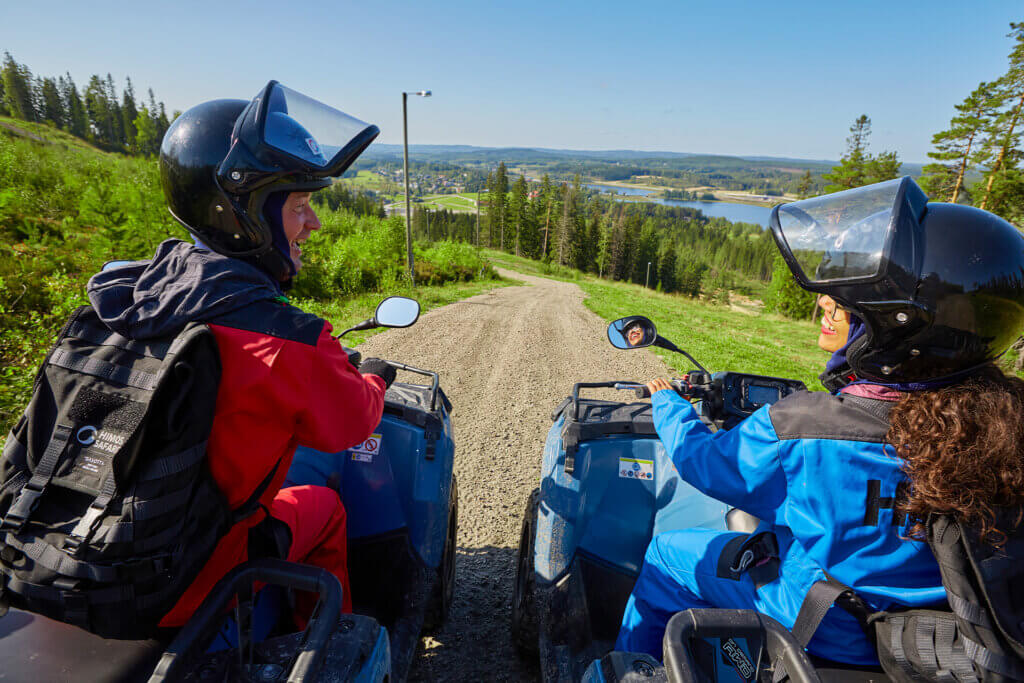Kaksi henkilöä katsovat hymyillen toisiaan mönkijöiden päällä Himoksen syksyisissä maisemissa.