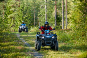 Mönkijät kuskeineen vihreässä metsässä.
