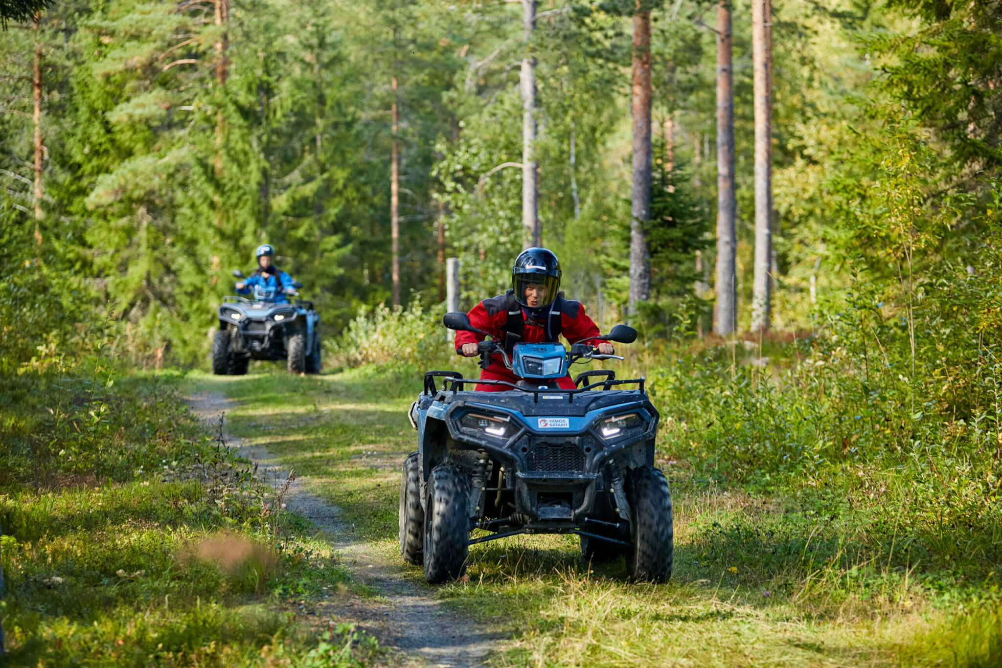 Mönkijät kuskeineen vihreässä metsässä.
