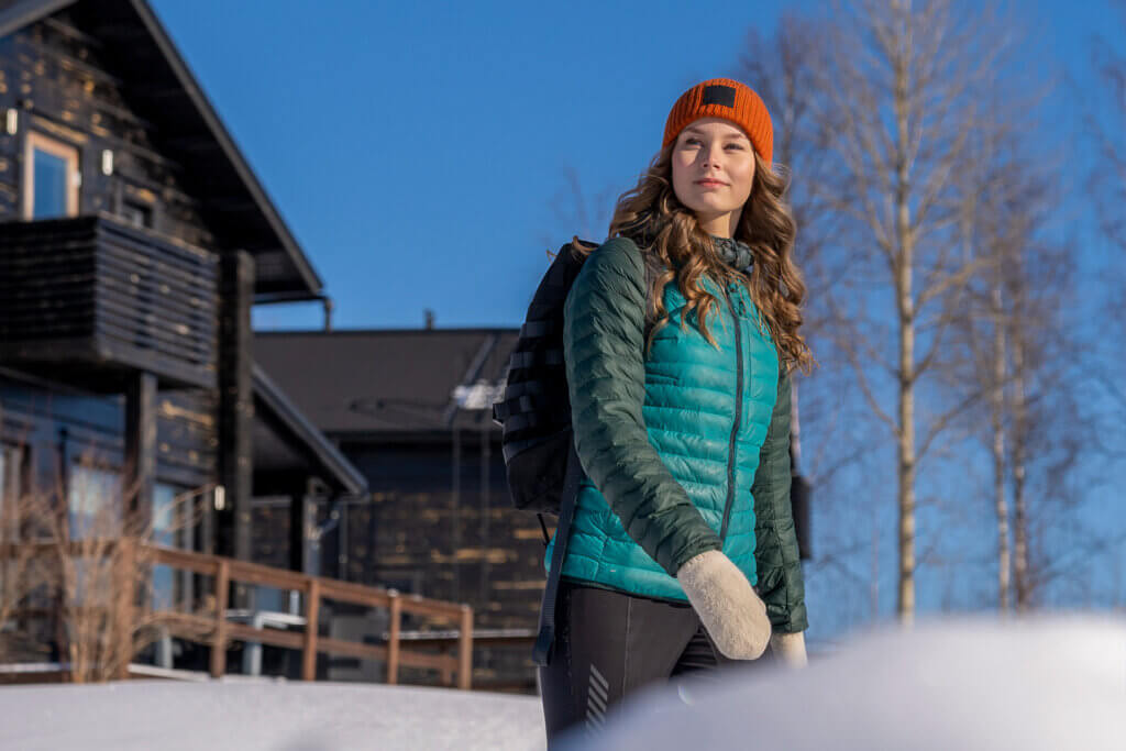 Nainen kävelyllä aurinkoisissa kevätmaisemissa.