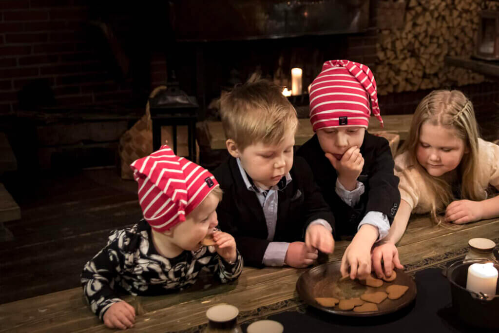 Lapset tonttuhatuissaan syövät joulun pipareita.