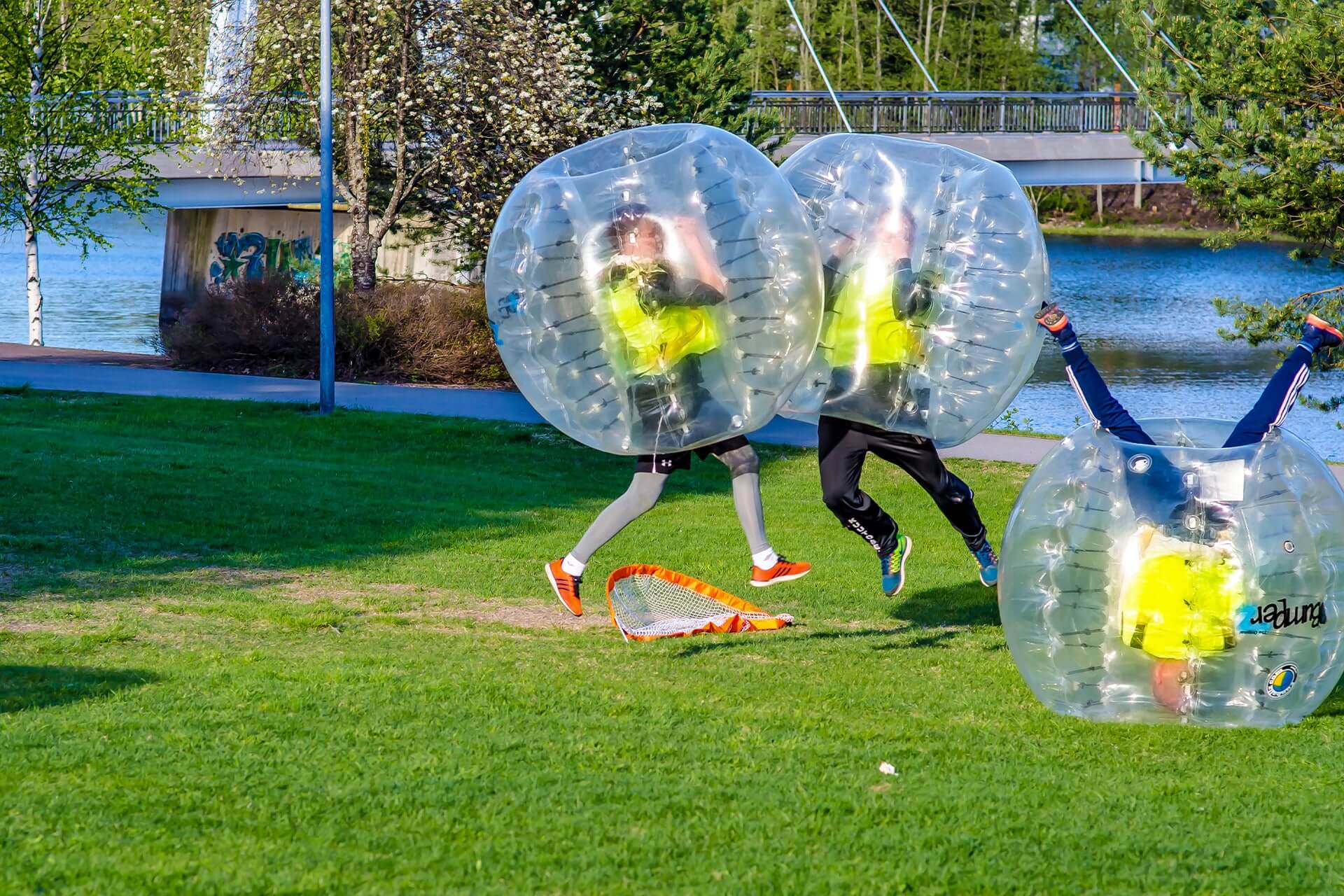 Kolme henkilöä pelaa superfutista, eli jalkapalloa oman kuplan sisällä.