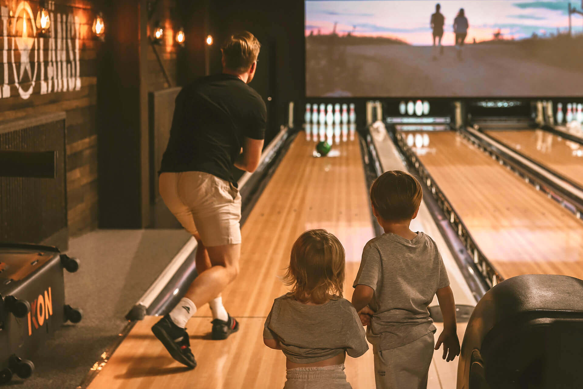 Mies ja kaksi lasta keilaamassa Willissä Lännessä.