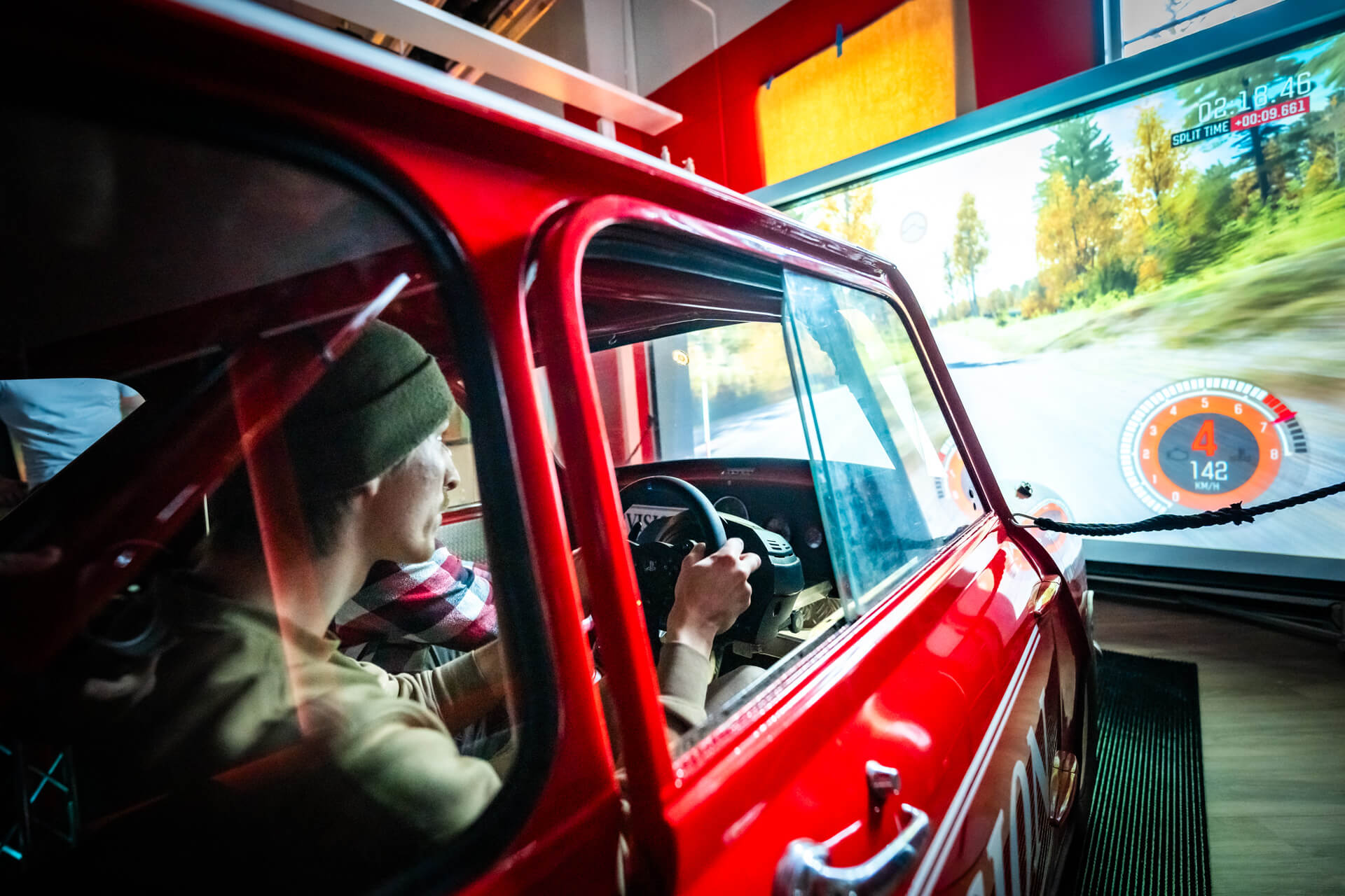 Mies ajaa punaista miniä rallisimulaattorissa.